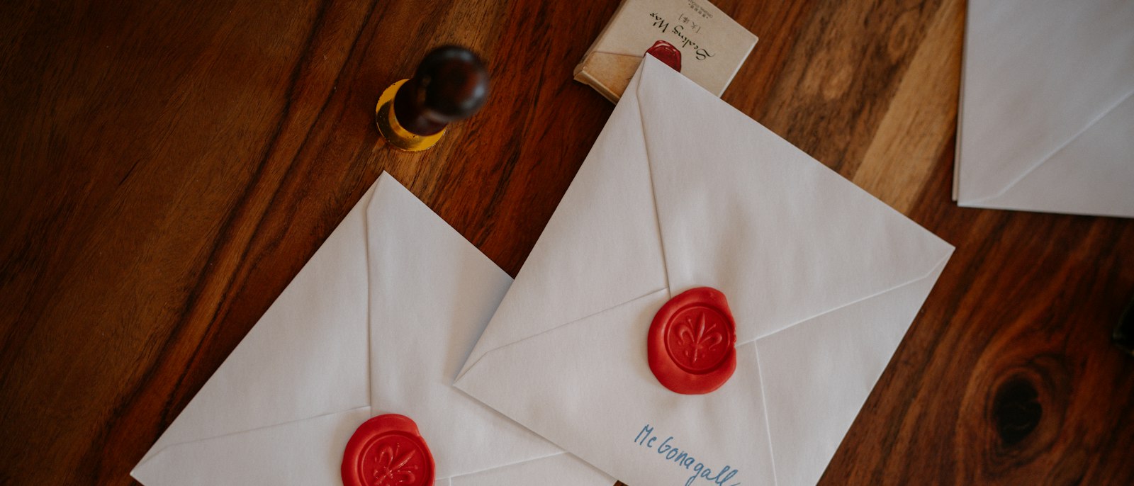 White envelopes sealed with red wax on a wooden table