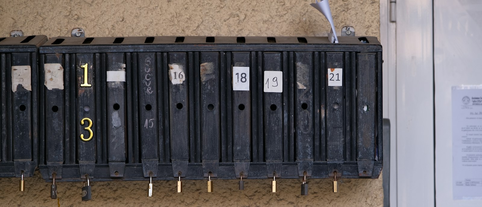 A row of numbered black mailboxes on a beige wall